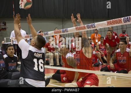 U.S. Marine Corps Sgt. Tyler Denney, left, and Cpl. Dakota Boyer, right, work together to make a hit against the 2017 DoD Warrior Games Team Army sitting volleyball team at McCormick Place in Chicago, June 30, 2017. The Warrior Games is an adaptive sports competition for wounded, ill and injured service members and veterans. Stock Photo