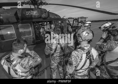 U.S. Army Sgt. Timothy Witts, a Black Hawk crew chief, briefs New Jersey Task Force One members on the hoist system during joint training at Joint Base McGuire-Dix-Lakehurst, N.J., June 28, 2017. The primary mission of New Jersey Task Force One is to provide advanced technical search and rescue capabilities to victims trapped or entombed in structurally collapsed buildings. Stock Photo