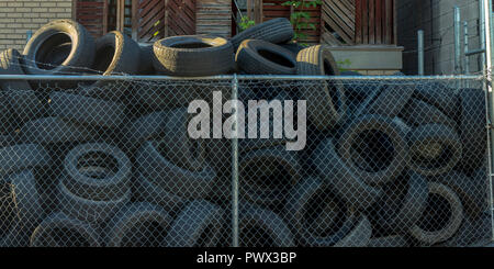 Old tires inside a mesh fence with barbed wire Stock Photo