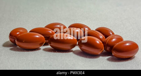 Orange pills on fabric textured white background Stock Photo