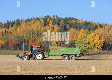 Salo, Finland - October 14, 2018: Farmer spreading manure on stubble field with Valtra tractor and Bergmann spreader on a beautiful day of autumn. Stock Photo
