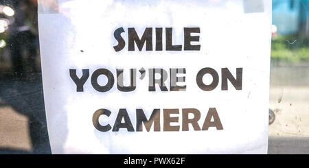 Smile youre on camera sign on a glass window Stock Photo