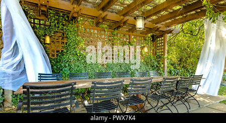 Table and chairs under a wooden pergola Stock Photo