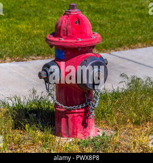 Weathered red fire hydrant on a grassy ground Stock Photo