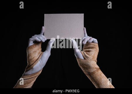 Spooky mummy holding a piece of cardboard, Halloween theme Stock Photo