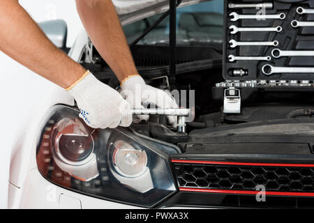 cropped image of auto mechanic auto mechanic repairing car with wrench on white Stock Photo