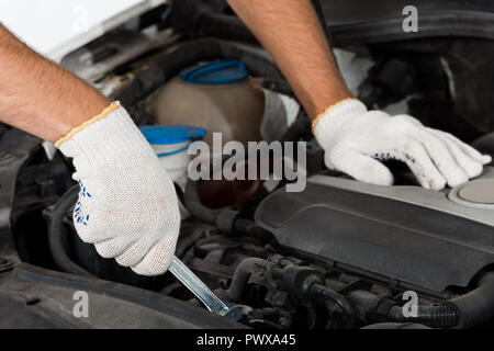 cropped image of auto mechanic repairing car with wrench Stock Photo