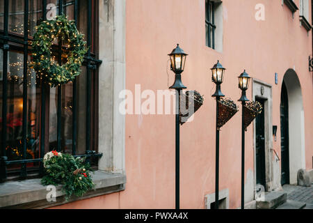 Christmas decorations of the building. Christmas wreaths on the windows and decorated lampposts with garlands next to the traditional European building in Warsaw. Stock Photo