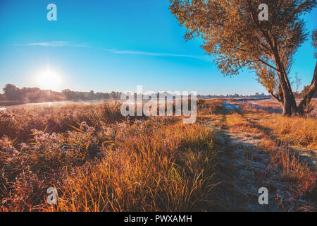Early morning, sunrise over the lake. Rural landscape in autumn, dirt road on the lake shore