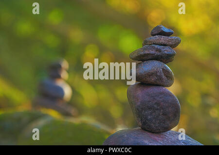 Stacked stone pyramid in front of green blurry background with bokeh Stock Photo