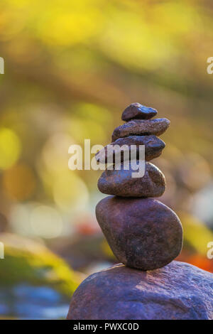 Stacked stone pyramid in front of green blurry background with bokeh Stock Photo