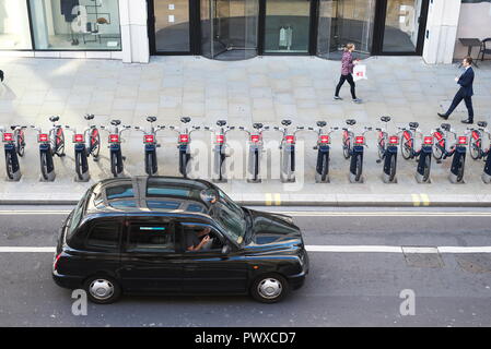 drone aerial photos of london black cab travels along a major A road in the city of London, with TFL boris Bikes/rent bikes racked up outside offices Stock Photo