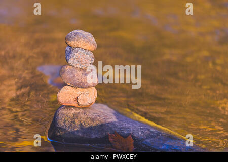 Stacked stone pyramid in front of yellow blurry background with bokeh Stock Photo