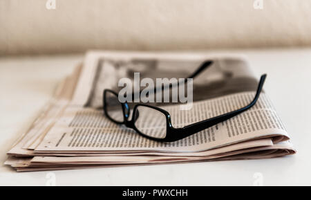 Old Spectacles or Glasses and Newspapers On a White Table Old Spectacles or Glasses and Newspapers On a White Table Stock Photo
