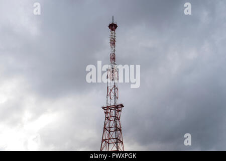 Telecommunication tower with panel antennas and radio antennas and satellite dishes for mobile communications 2G, 3G, 4G, 5G with red fence around tow Stock Photo