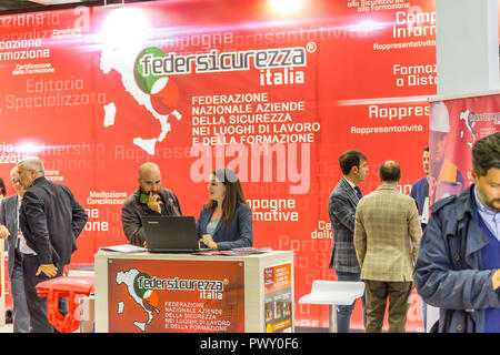 Bologna, Italy.  17th October, 2018. booth presenter welcomes visitor. AMBIENTE LAVORO is the first Italian fair dedicated to safety and health at work. GoneWithTheWind/Alamy Live News Stock Photo