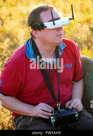 Drone pilot seen wearing a first-person view headset. Young man driving a quad-copter using video-goggles Stock Photo