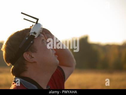Drone pilot seen wearing a first-person view headset. Young man driving a quad-copter using video-goggles Stock Photo