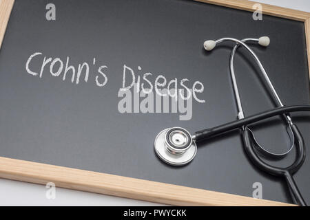 Word Crohn's Diseasewritten in chalk on a blackboard black next to a stethoscope, conceptual image Stock Photo