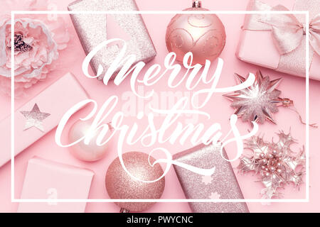 Pink christmas gifts isolated on pastel pink background. Wrapped xmas boxes, christmas ornaments and baubles. Stock Photo