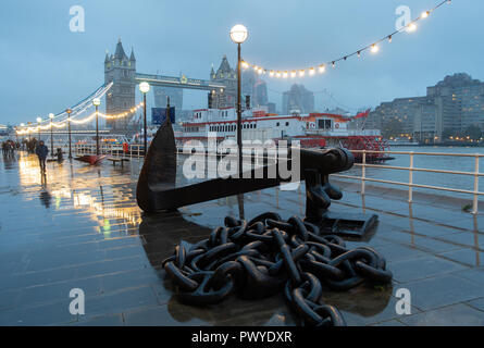 A Wet Early Evening on Butlers Wharf with the Dixie Queen Paddle Steamer, Large Chain and Anchor, Tower Bridge on South Bank River Thames London UK Stock Photo