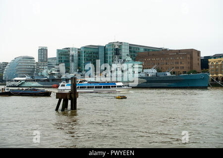 The Famous World War Two Light Cruiser HMS Belfast Moored in the River Thames with a Passing Tourist Boat and the South Bank London England UK Stock Photo