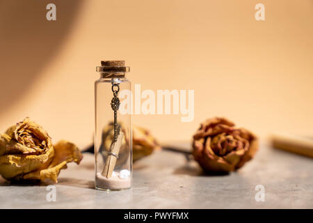 vintage metal key, sand and paper letter roll in glass bottle Stock Photo