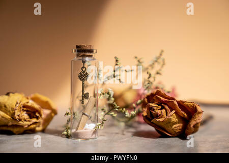 vintage metal key, sand and paper letter roll in glass bottle Stock Photo