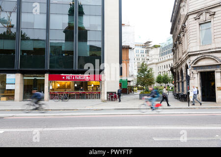 London, UK. Two cyclists ride past a quiet branch of Pret a Manger. Stock Photo