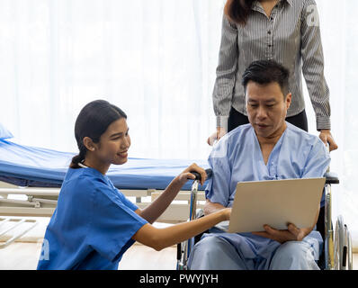 Physical therapist explain treatment method to senior patient and relative using notebook Stock Photo