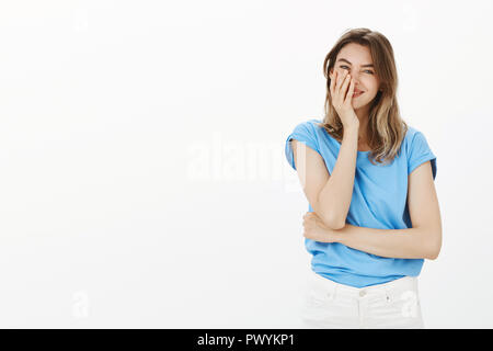 Girl cannot believe she has caring boyfriend. Happy carefree attractive woman in blue t-shirt, smiling broadly and holding palm on face, blushing, being pleased receiving great unexpected gift Stock Photo