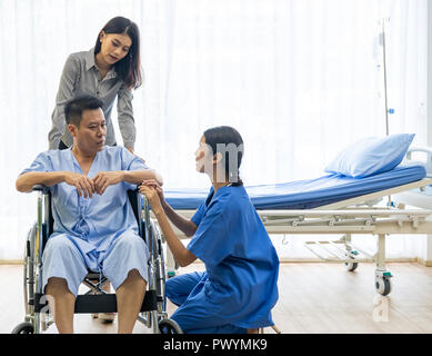 Physical therapist explain treatment method to senior patient and relative Stock Photo