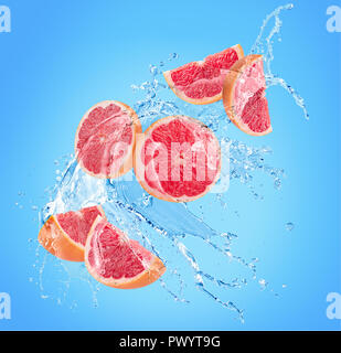 grapefruit slices in water splash on a blue background. Stock Photo