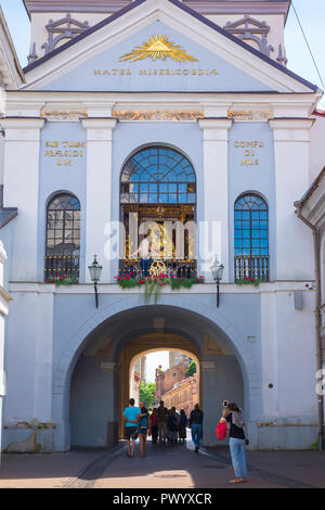 Chapel of the Gates of Dawn, in Vilnius Old Town a woman takes a photo of people visiting the chapel and shrine of the Madonna of the Gates of Dawn. Stock Photo