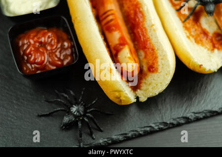 Creepy Halloween hotdog fingers on the black table, party food Stock Photo