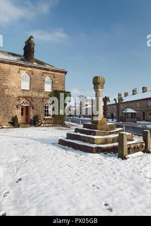 Snowy winter view of the Boars Head Hotel in Ripley in North Yorkshire, with the market cross and stocks in front of the hotel Stock Photo