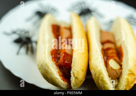 Creepy Halloween hotdog fingers on the black table, party food Stock Photo
