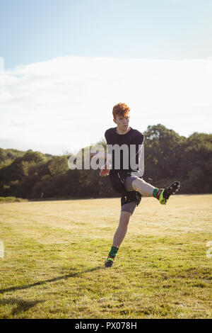 Football player kicking football in the field Stock Photo