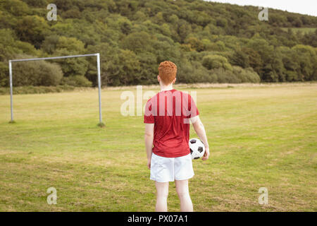 Football player standing with soccer ball in the field Stock Photo