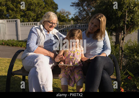 Multi-generation family looking at photo album in garden Stock Photo