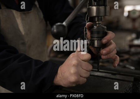Blacksmith using press drill in workshop Stock Photo