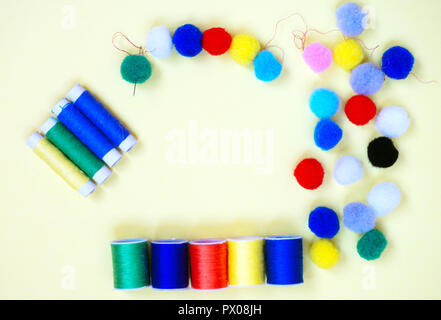 Sewing accessories in different colors, threads, needle and pompons, flat lay Stock Photo
