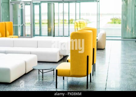 Office waiting area interior with white sofas and yellow chairs Stock Photo