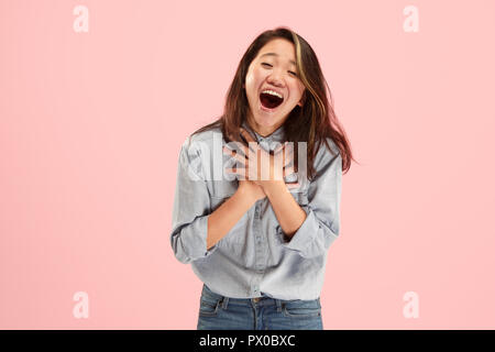 Delight. Beautiful female half-length front portrait isolated on pink studio backgroud. Young, emotional, smiling, surprised woman standing. Human emotions, facial expression concept. Trendy colors Stock Photo