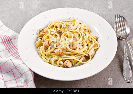 Delicious salmon pasta dish, tagliatelle or linguine noodles. High angle view of fresh spaghetti pasta with herbs and grilled salmon. Stock Photo