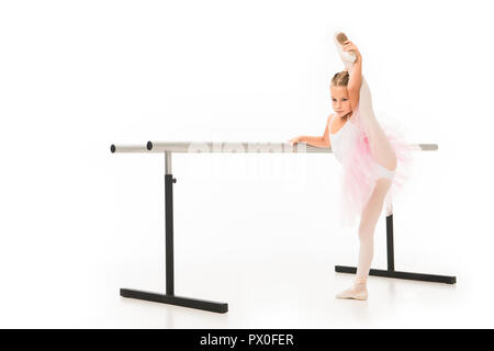 Cute little ballerina in a lilac dress and white tights in white ballet  flats doing leg stretches Stock Photo - Alamy