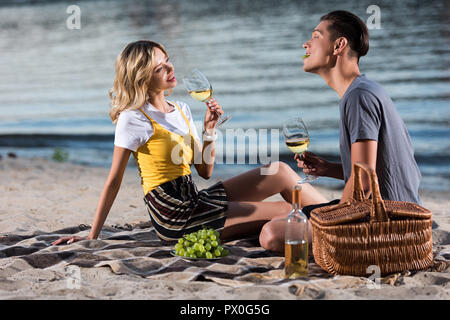 young couple having fun at picnic on river beach in evening Stock Photo