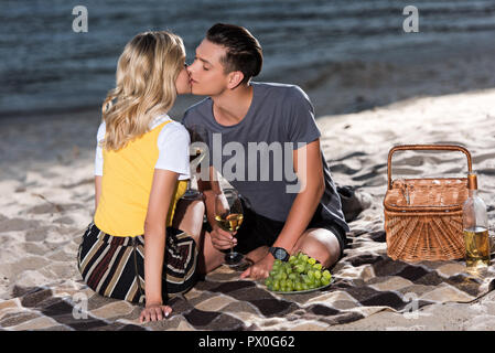 young couple kissing at picnic on river beach in evening Stock Photo