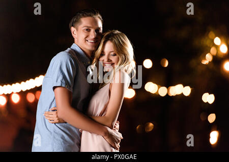 smiling young couple hugging on river beach in evening Stock Photo