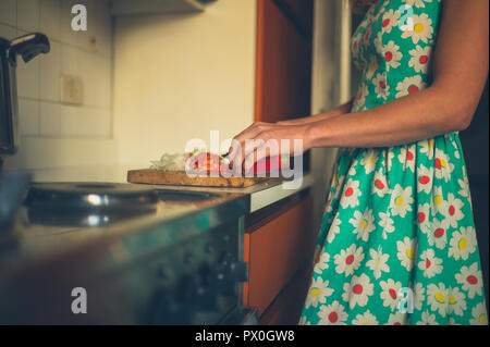 A young woman is cooking dinner in her kitchen